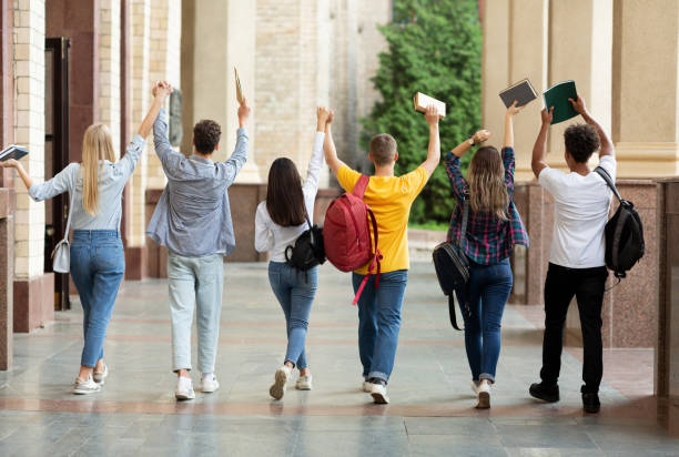 We passed exams. Students raised hands and walking in college campus after the last test